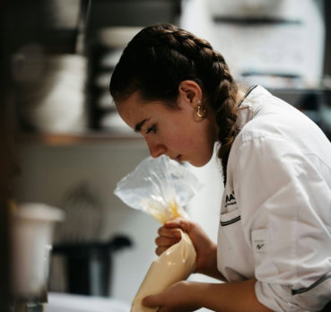 A woman in a kitchen preparing food on a cutting board