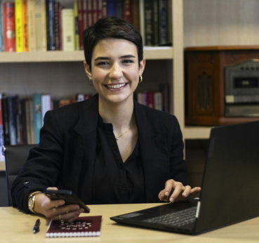 A woman smiles while working on a laptop.